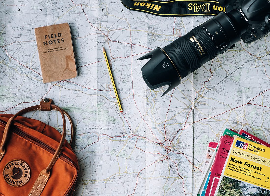 Map, field notes, camera and backpack laid out on a desk
