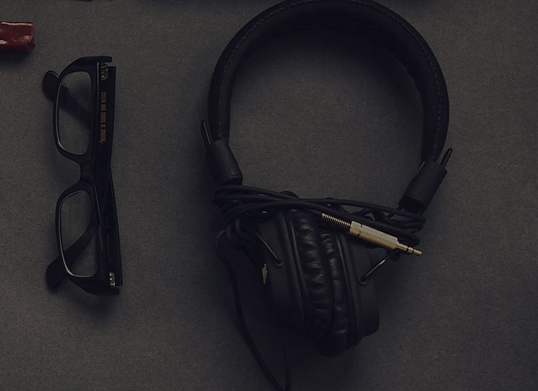 Glasses and headphones on a dark desk