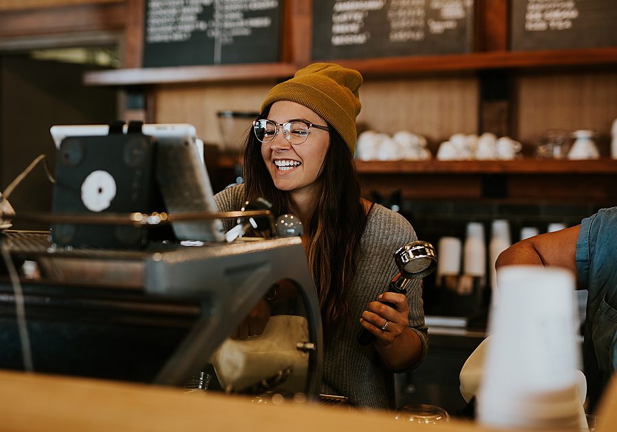 Small business owner smiling behind the counter of her shop