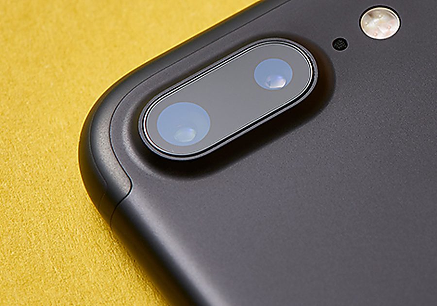 Close-up of a smartphone camera on a yellow background