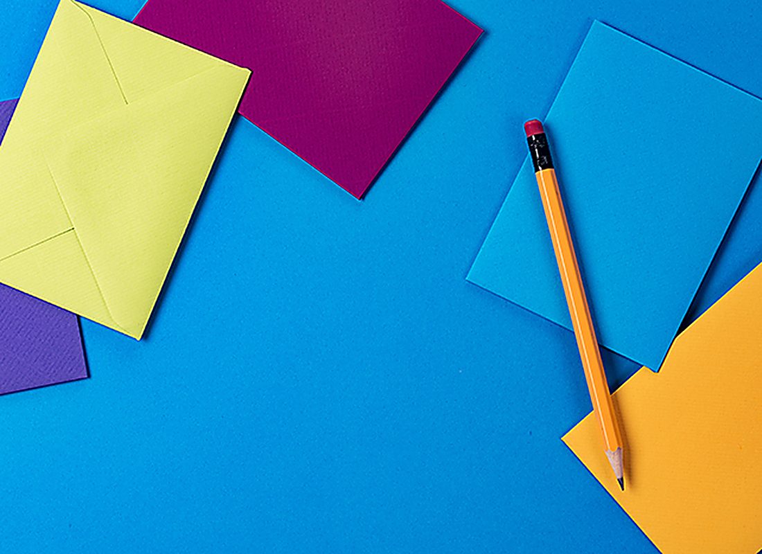 Sheets of coloured paper and a pencil arranged on a desk